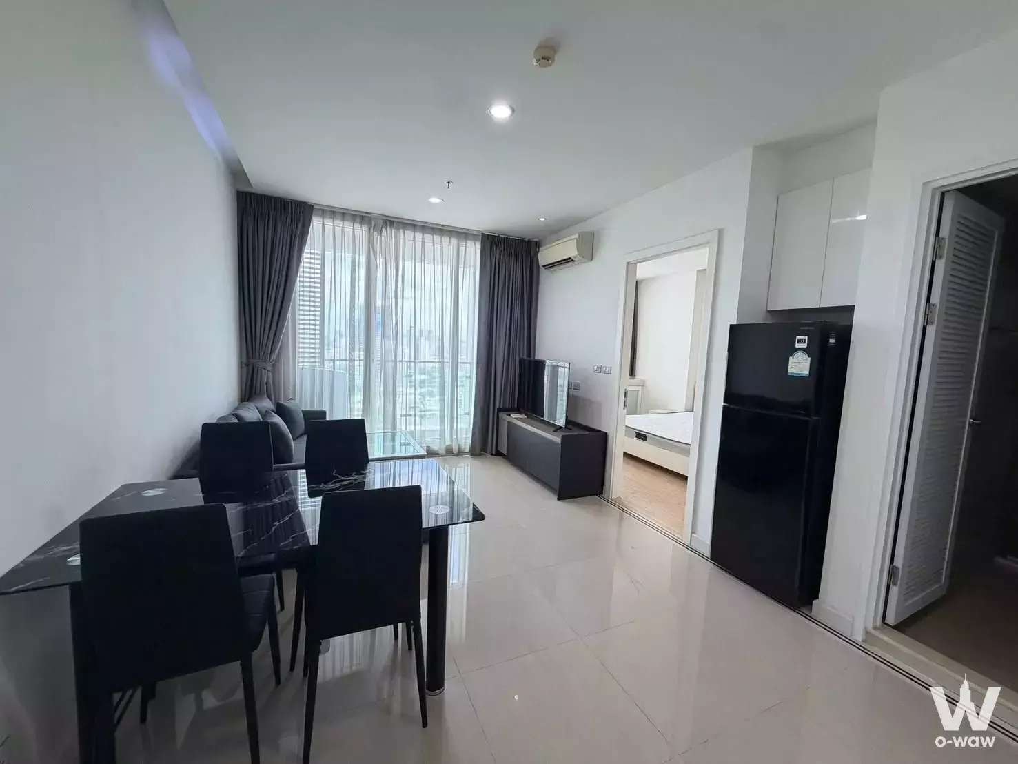 Open-plan living area in TC Green Rama 9 with black dining set and balcony access