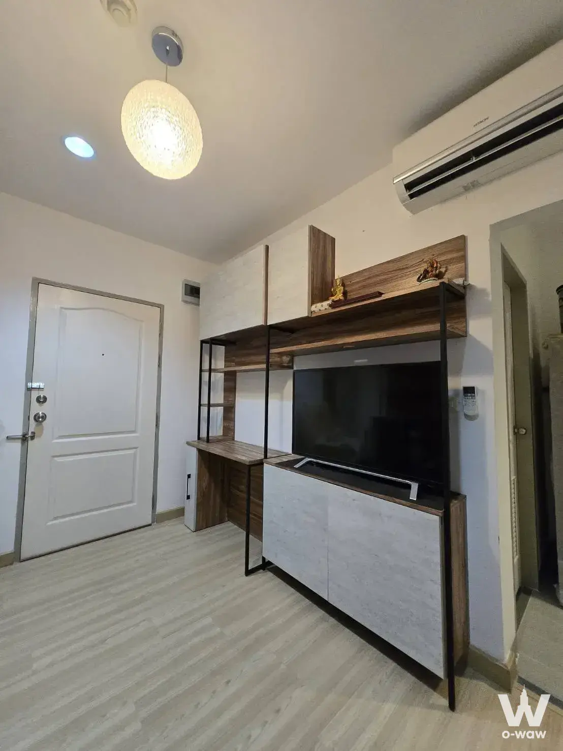 Minimalist living room for sale in The Kith Tiwanon studio unit with built-in walnut entertainment unit and TV