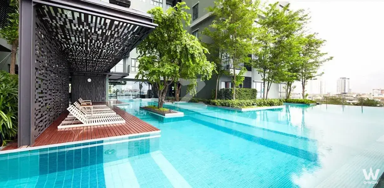 Infinity pool with wooden deck and lounge chairs at Teal Sathon-Taksin, a luxury 1-bed condo rental