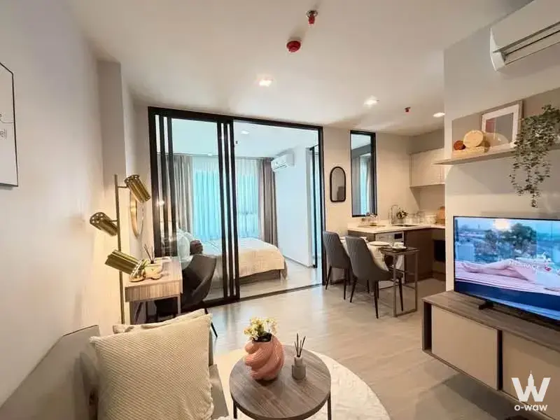 Life Sathorn Sierra living room with coral accents and open bedroom partition