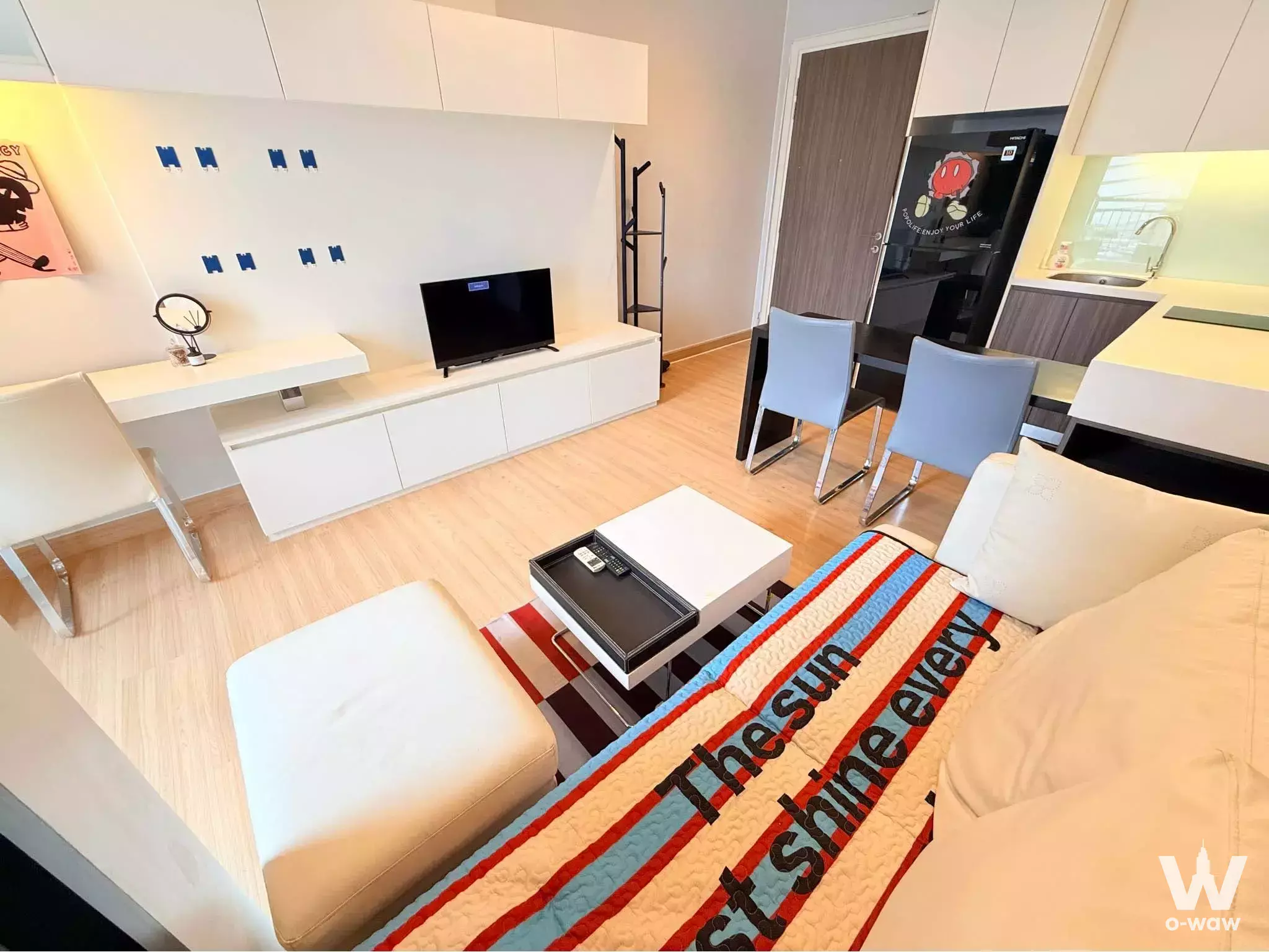 Open-plan studio with beige sofa, white media console, and compact kitchenette in 1-bed Urbano Absolute Sathon-Taksin condo