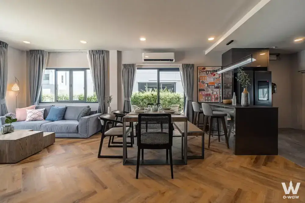 Open-plan living space with herringbone oak floors and dark kitchen island in this Centro Bangna house for rent