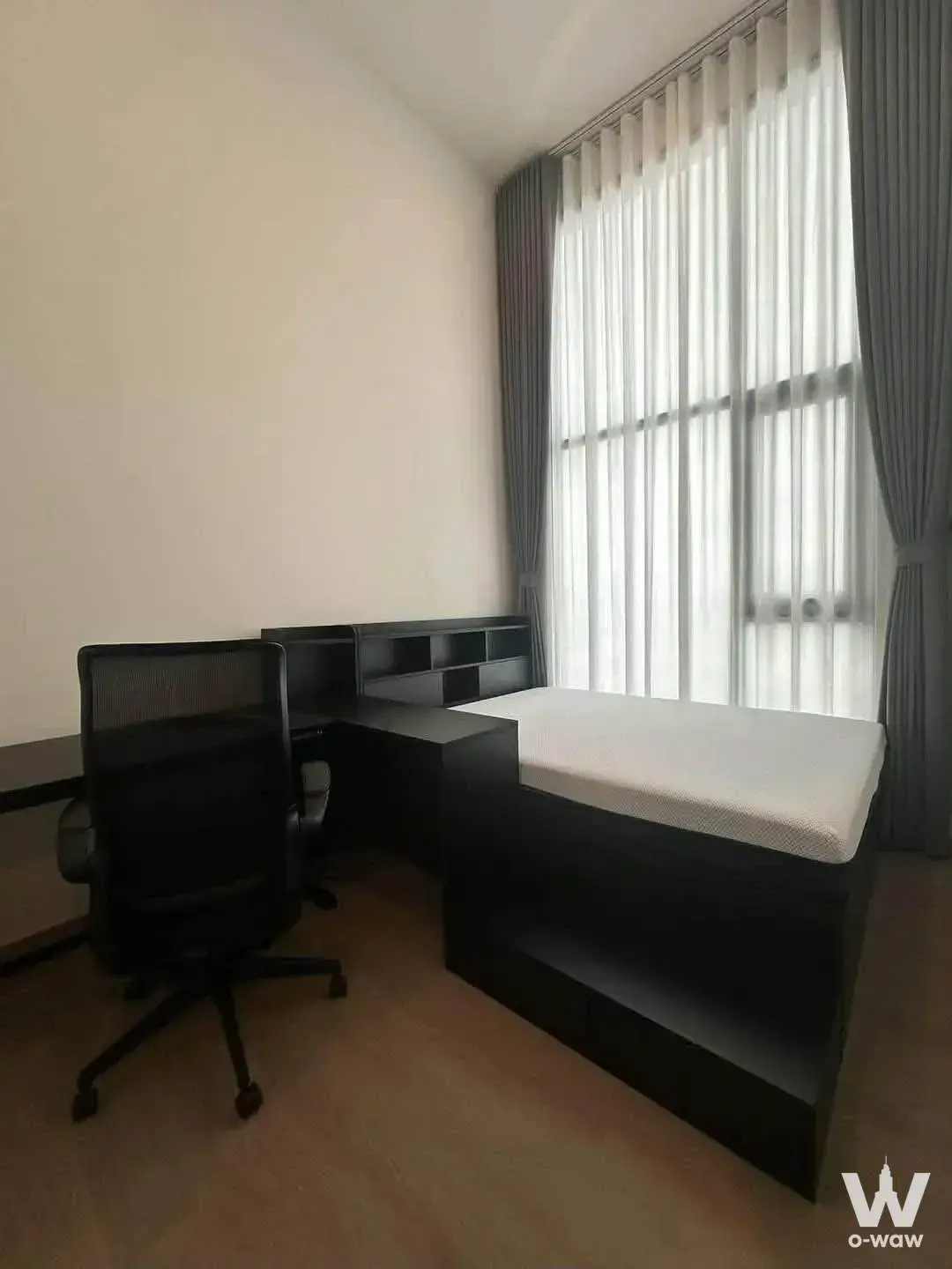 Semi-furnished bedroom-study in a 2-bed condo for rent at Origin Play Bangkhunnon with black desk and floor-to-ceiling window