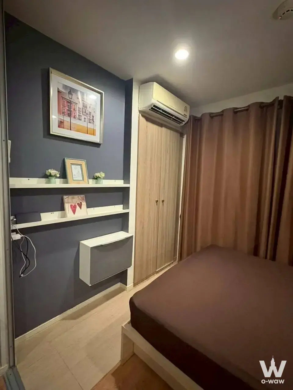 Compact bedroom featuring blue accent wall, floating desk, and tall wardrobe in Lumpini Ville On Nut 46