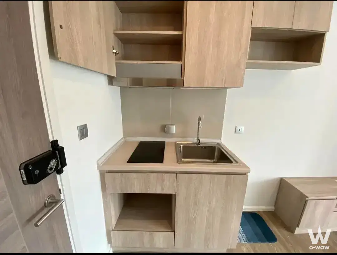 Compact kitchenette with induction cooktop and light wood cabinets in Modiz condo