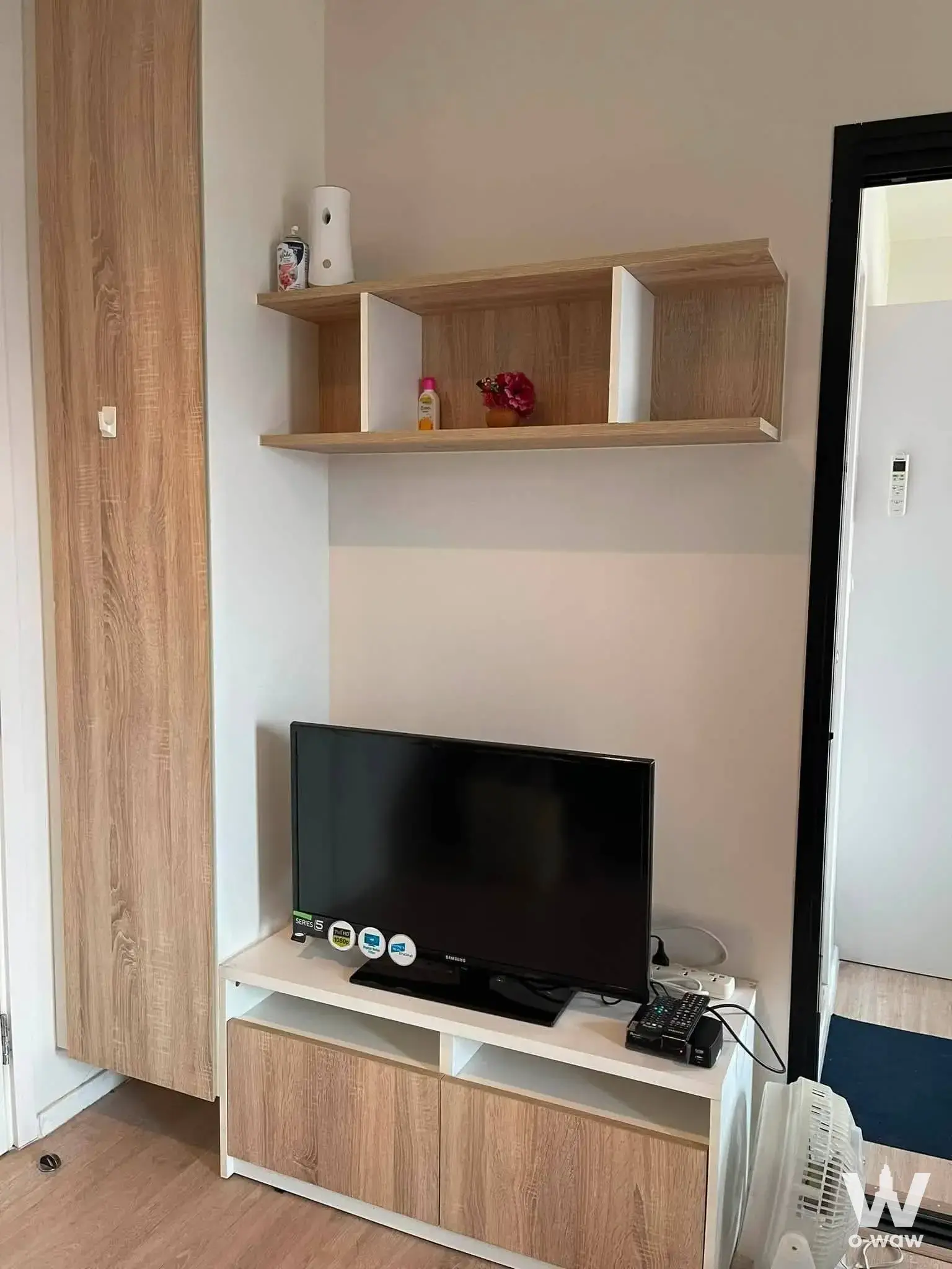 Living room with light wood wardrobe and TV setup in Escent Chiang Mai condo