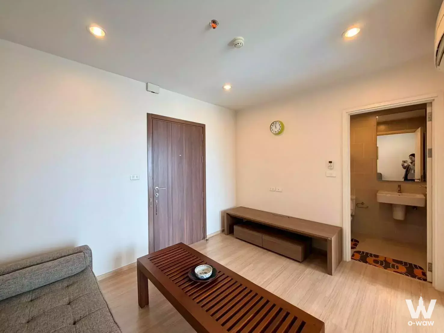 Studio living area in THE BASE Chaengwattana with grey sofa and wooden console