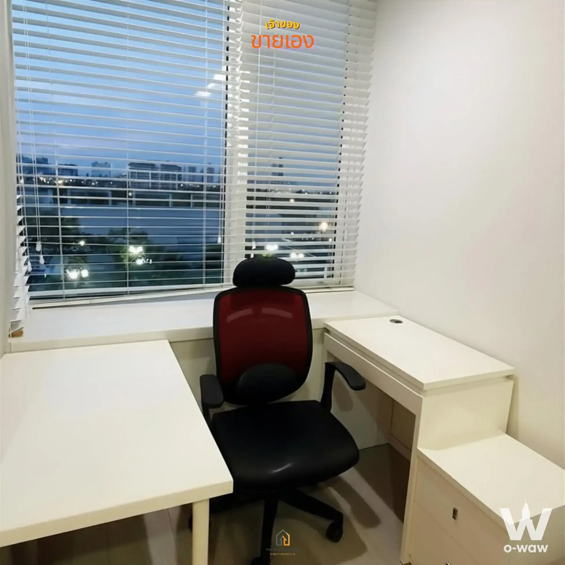 Compact home office nook in TC Green Rama 9 with L-shaped white desk and evening city view through blinds