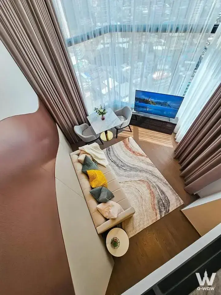 Modern living space in Park Origin Chula-Samyan 2-bed condo with wood floors, patterned rug, and city view