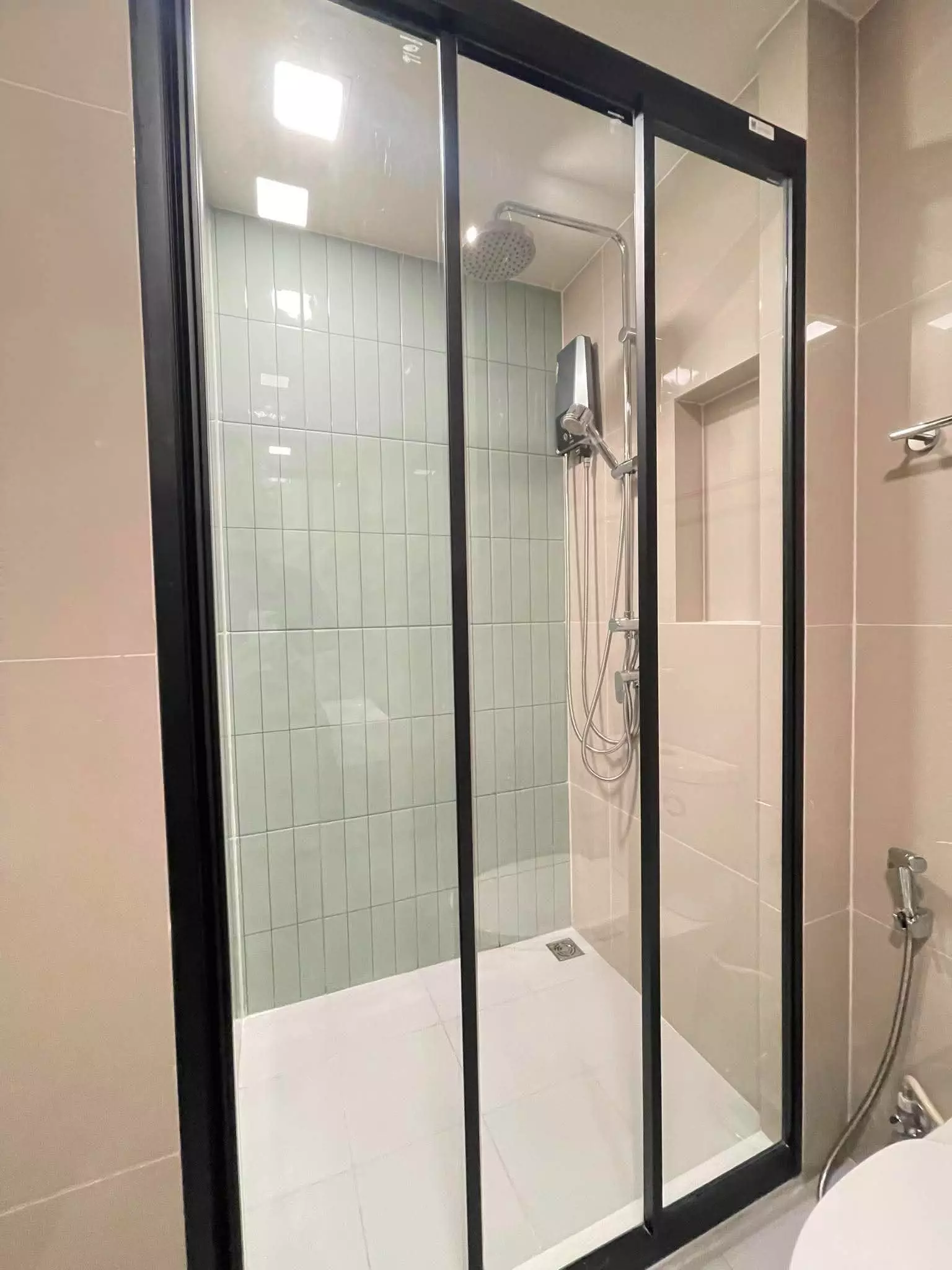 Modern bathroom in FLO by Sansiri 1-bed rental with green-tiled walk-in shower and chrome rainfall head
