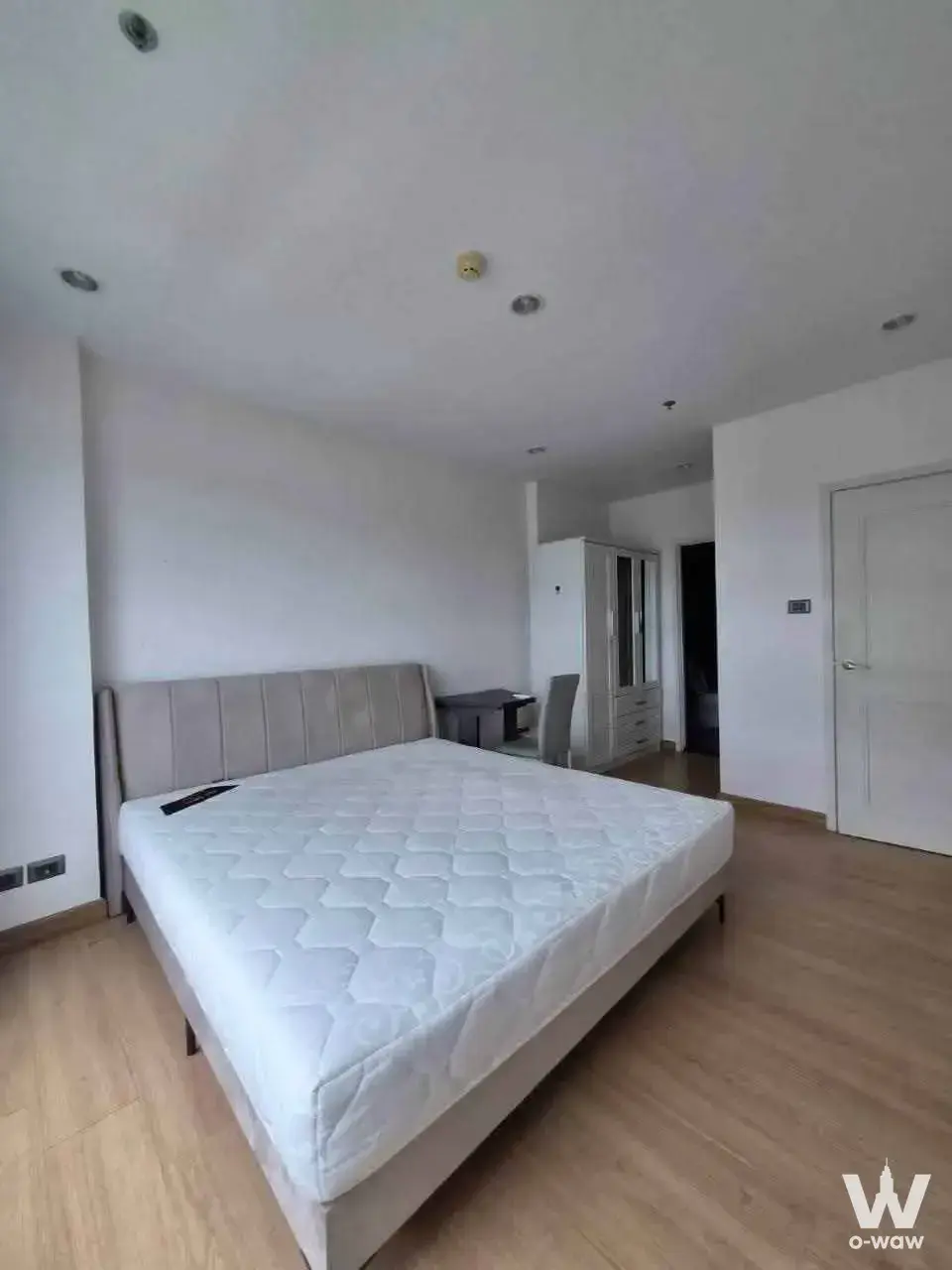 Queen bed with tufted headboard and glass wardrobe in the bedroom of a 1-bed condo for rent in Supalai Wellington II