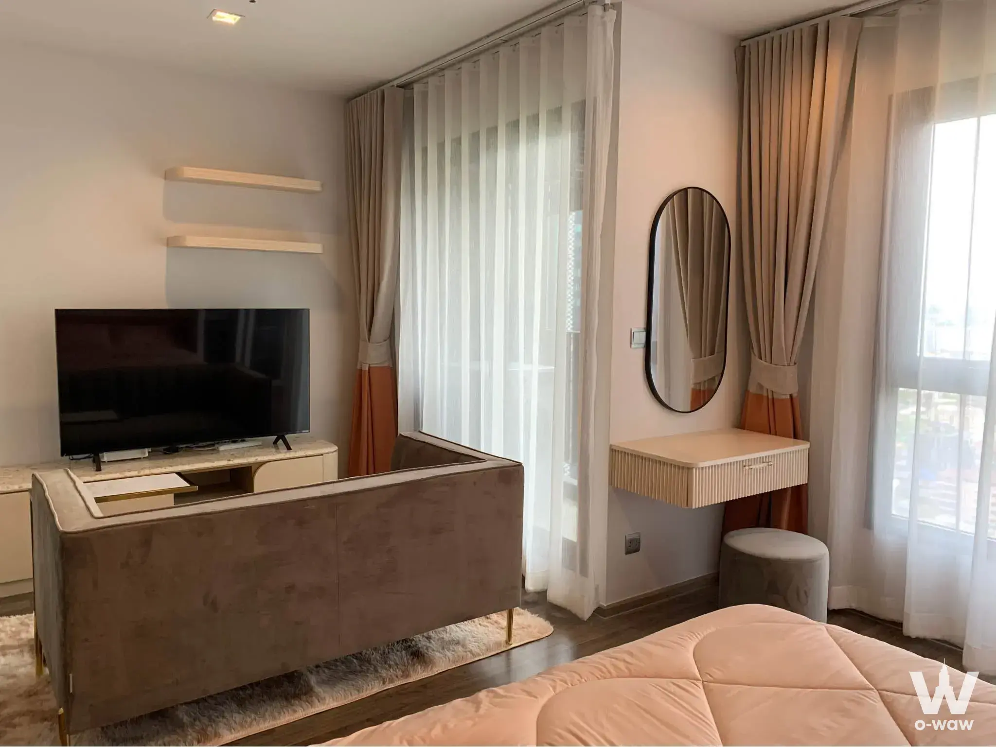 Furnished studio apartment with taupe sofa, marble TV console, and large city-view windows