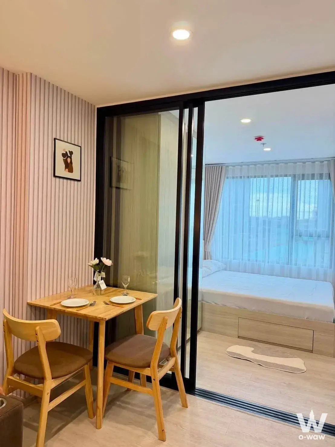 Studio dining set in Origin Plug & Play condo with wood table and glass-partitioned bedroom