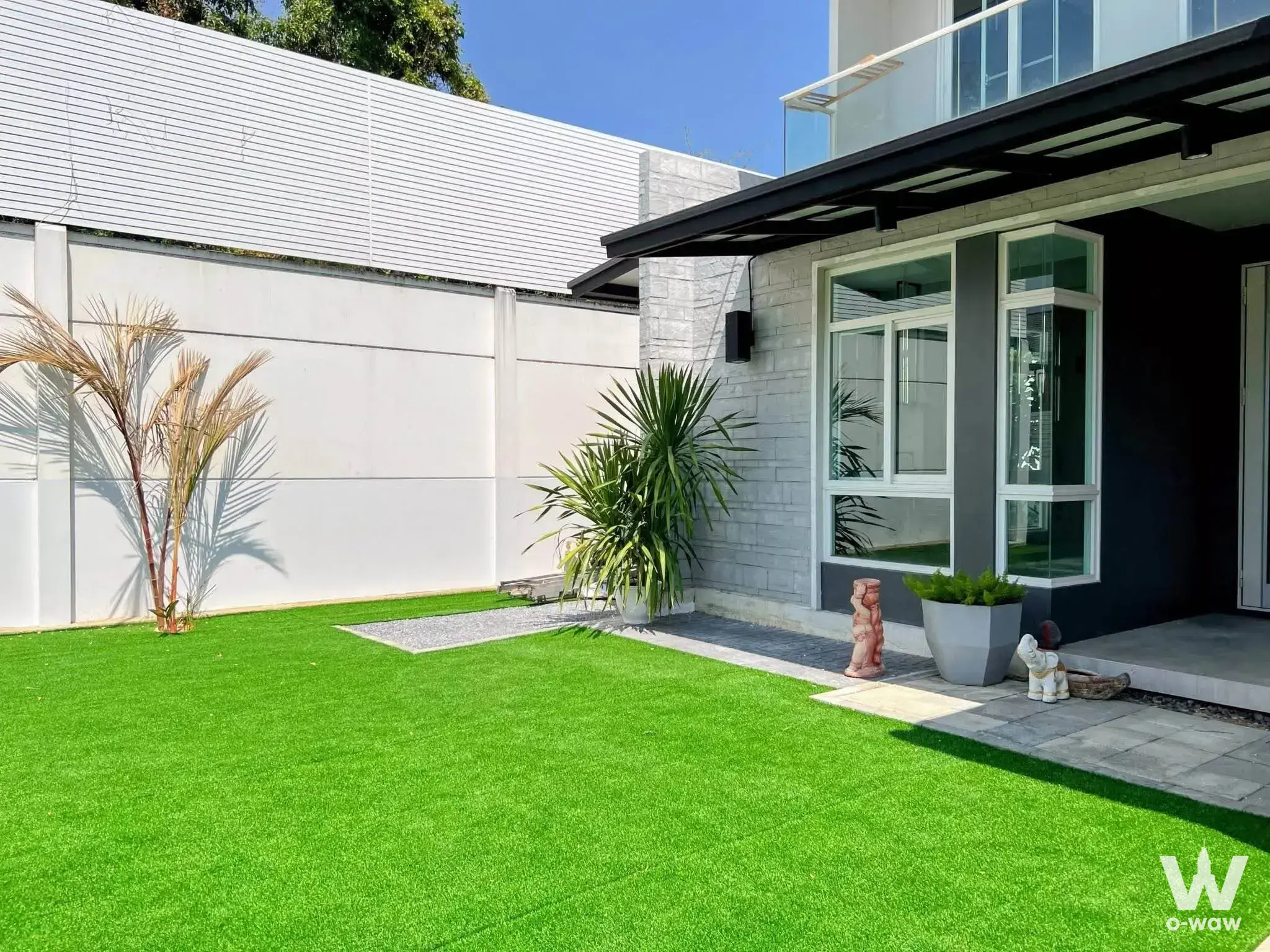Modern house exterior with green turf garden and grey stone facade at Mantana 2 Bangna KM 7 rental