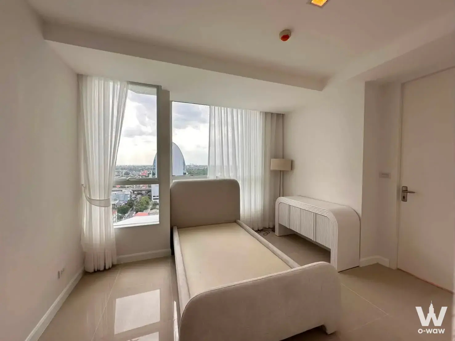 Minimalist bedroom in My Resort @ River condo featuring beige tile floors and city views from large windows
