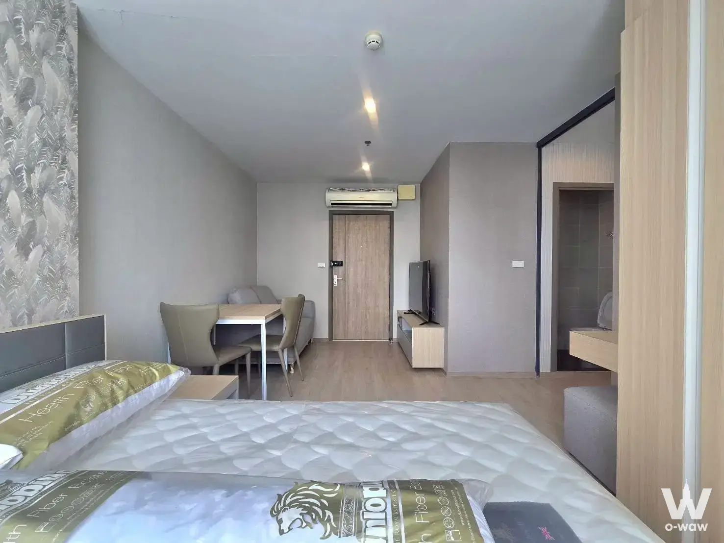 Bedroom with grey headboard and tropical wallpaper in 1-bed condo for rent at Ideo O2