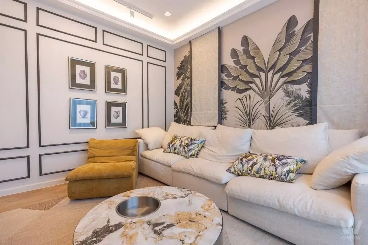 Spacious living room in Setthasiri Bangna 4-bed house with sectional sofa, tropical leaf wallpaper, and marble coffee table