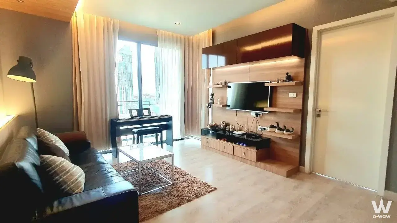 Living room in The Room Sukhumvit 62 2-bed condo with leather sofa and piano