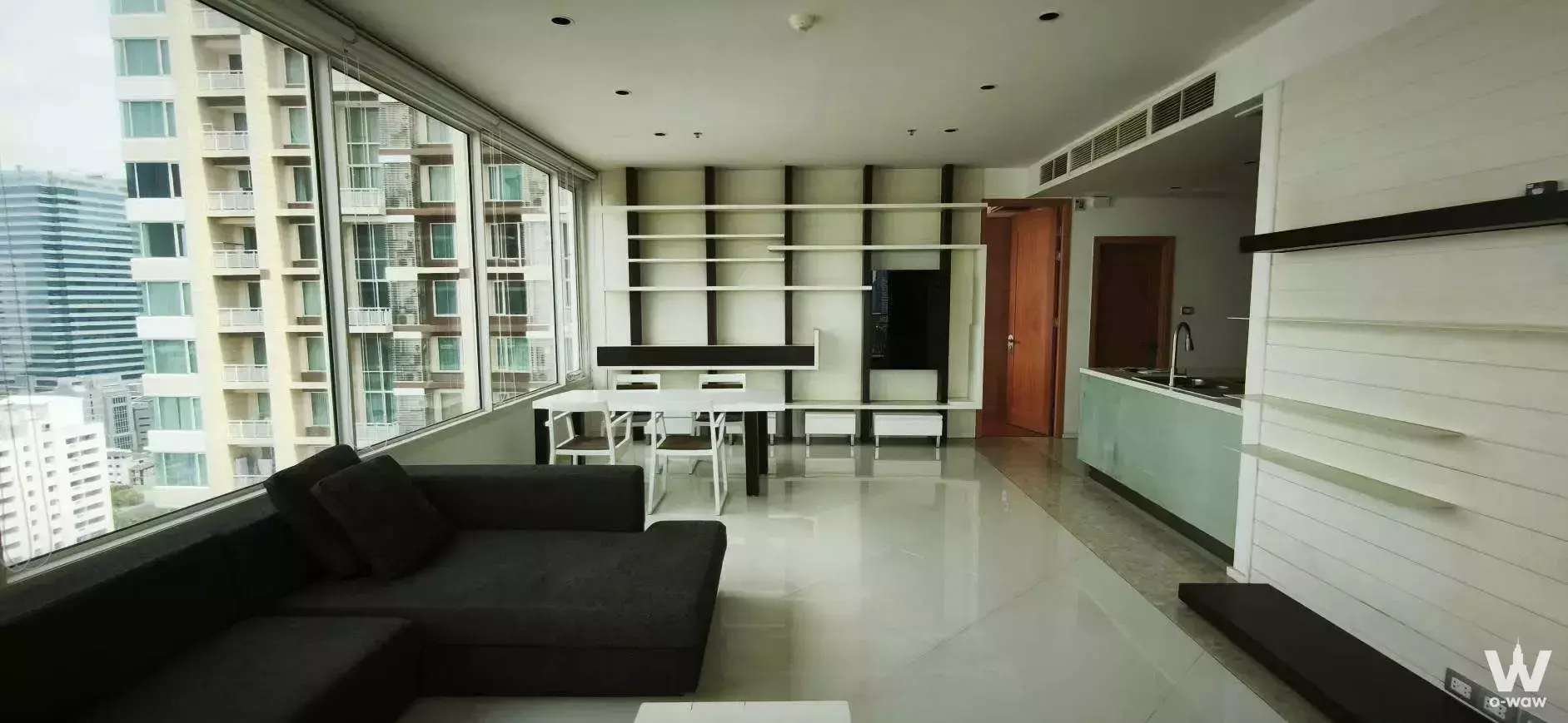 THE EMPIRE PLACE SATHON living room with charcoal sofa, dining set, and light green kitchen cabinetry