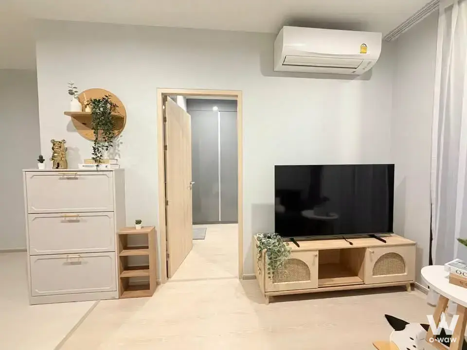 Bright living room in a Skyrise Avenue condo with light wood floors and a rattan media console