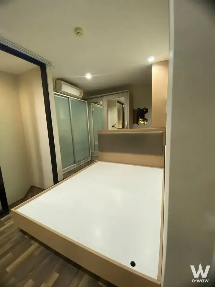 Modern 1-bed condo bedroom in Beyond Sukhumvit with light wood platform bed and frosted glass wardrobe