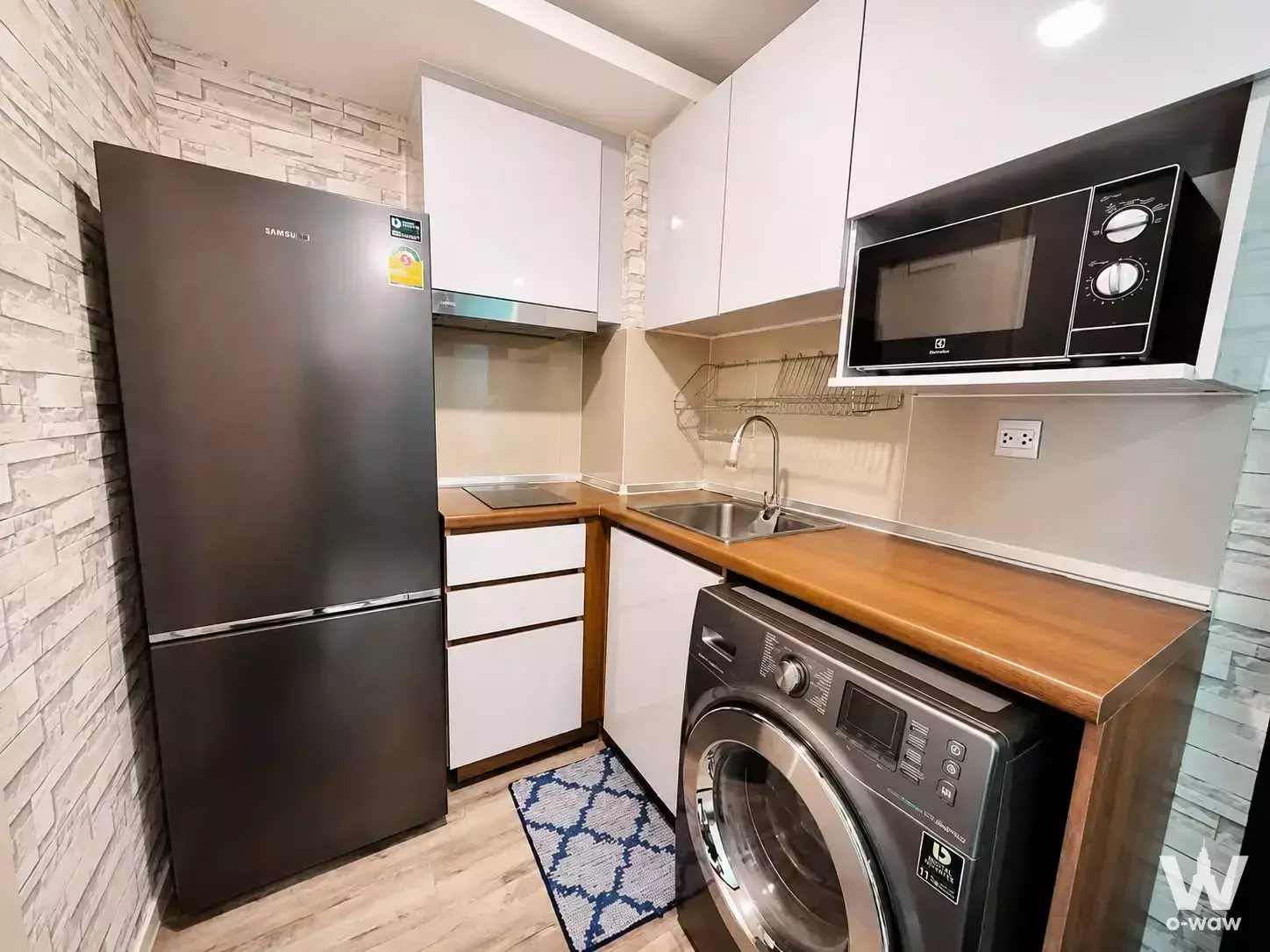 Compact kitchen in Modiz Ratchada 32 condo featuring wood counters, fridge, and washing machine