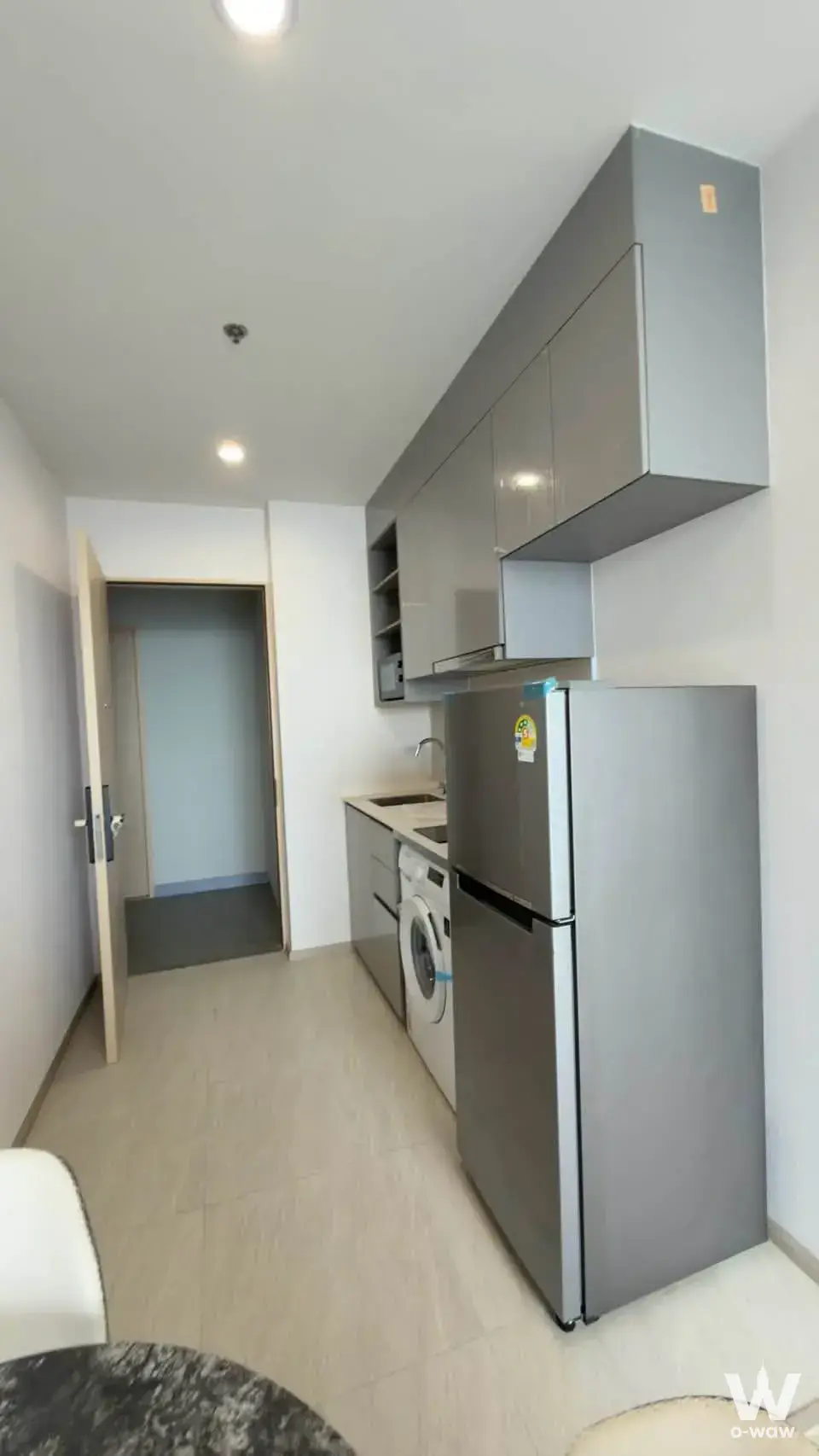 Tidy kitchenette with grey cabinetry and stainless steel fridge in a 2-bed condo for rent at Skyrise Avenue Sukhumvit 64