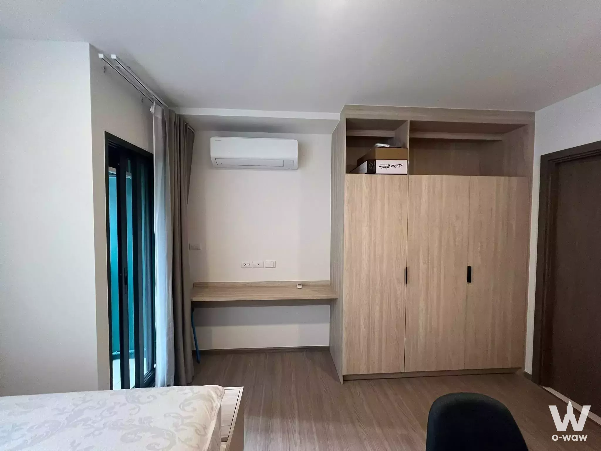 Bedroom with oak laminate floors, built-in wardrobe, and balcony access in The Muve Pradipat condo