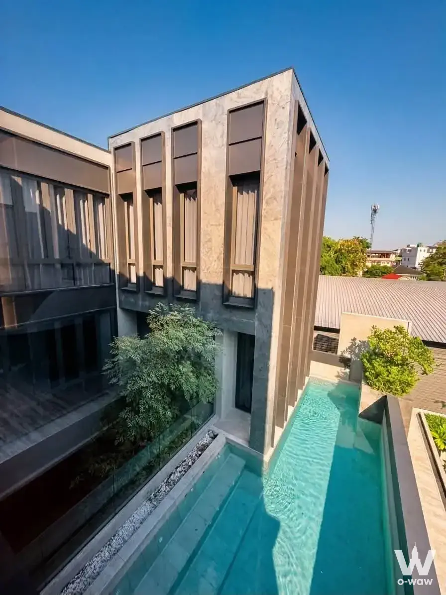 Rooftop lap pool at 5-bed house for rent in BuGaan Pattanakarn featuring turquoise water, glass railings, and beige stone