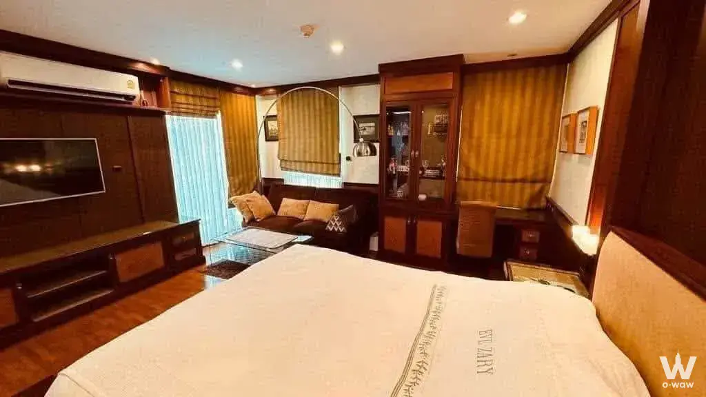 1-bed master suite in Baan Sirisathorn Suanplu with dark-wood paneling and gold accent pillows