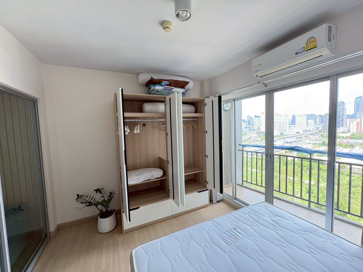 Spacious bedroom in Supalai Veranda Rama 9 rental with open wardrobe, AC unit, and balcony city view