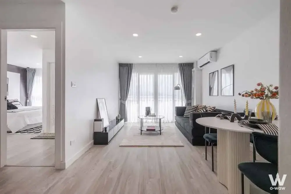 Open-plan living and dining area in a 2-bed condo for sale in Baan Ruenrom Bangna has teal dining chairs
