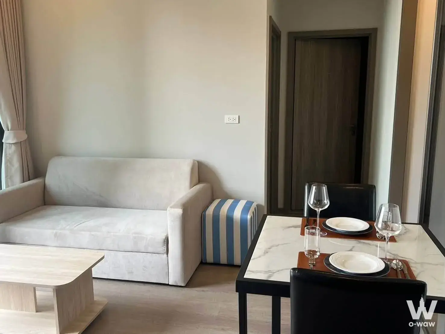 Furnished living room in a Whizdom The Forestias rental featuring a beige sofa and a set dining table for two