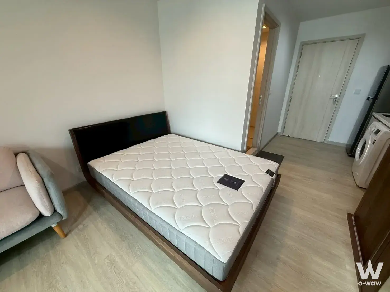 Studio bedroom in Life One Wireless condo featuring platform bed, washing machine, and wardrobe