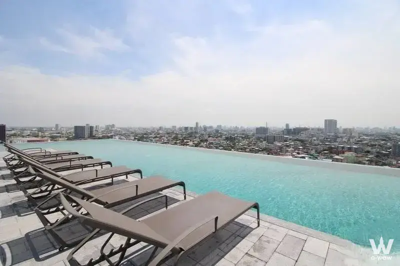 Rooftop infinity pool at Supalai Park Yaek Fai Chai Station with city skyline view and lounge chairs