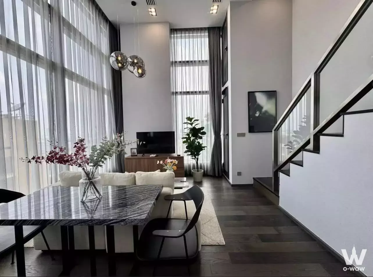 Modern duplex living area in Conner Ratchathewi with dark wood floors, marble dining table, and floor-to-ceiling windows