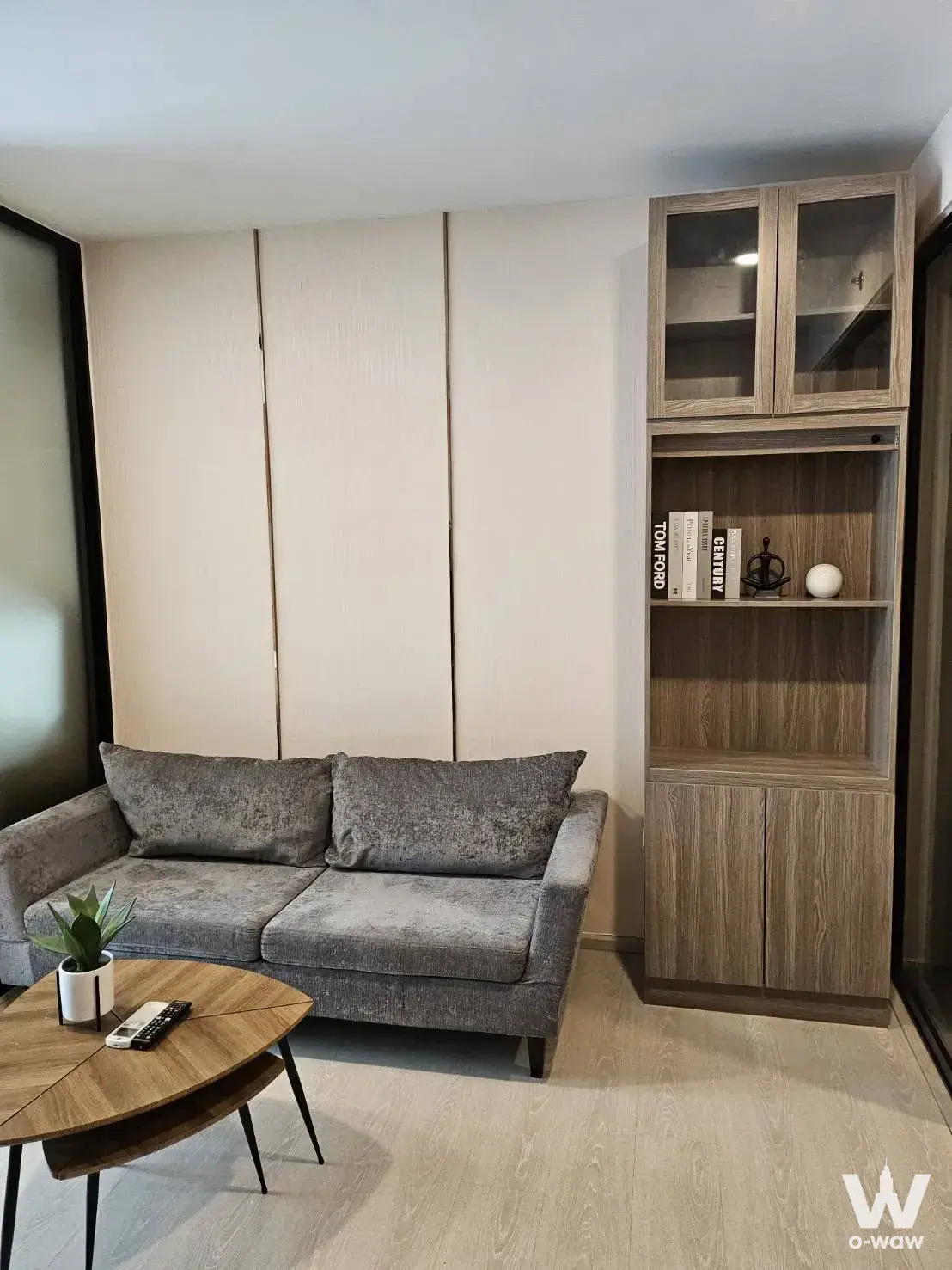 Living room of a 2-bed condo for rent at KnightsBridge Phaholyothin with a grey sofa, coffee table, and built-in cabinet