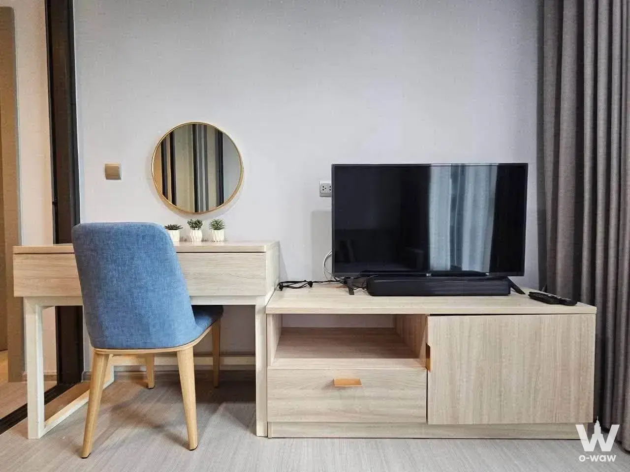 Modern bedroom featuring a light wood desk, blue chair, and TV unit in this Life Asoke 1-bed rental