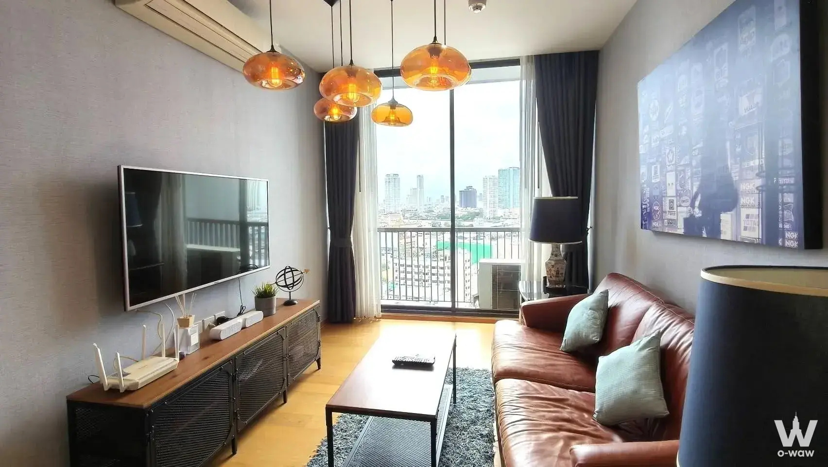 1-bed condo for rent in Noble Revo Silom with brown leather sofa and city skyline view