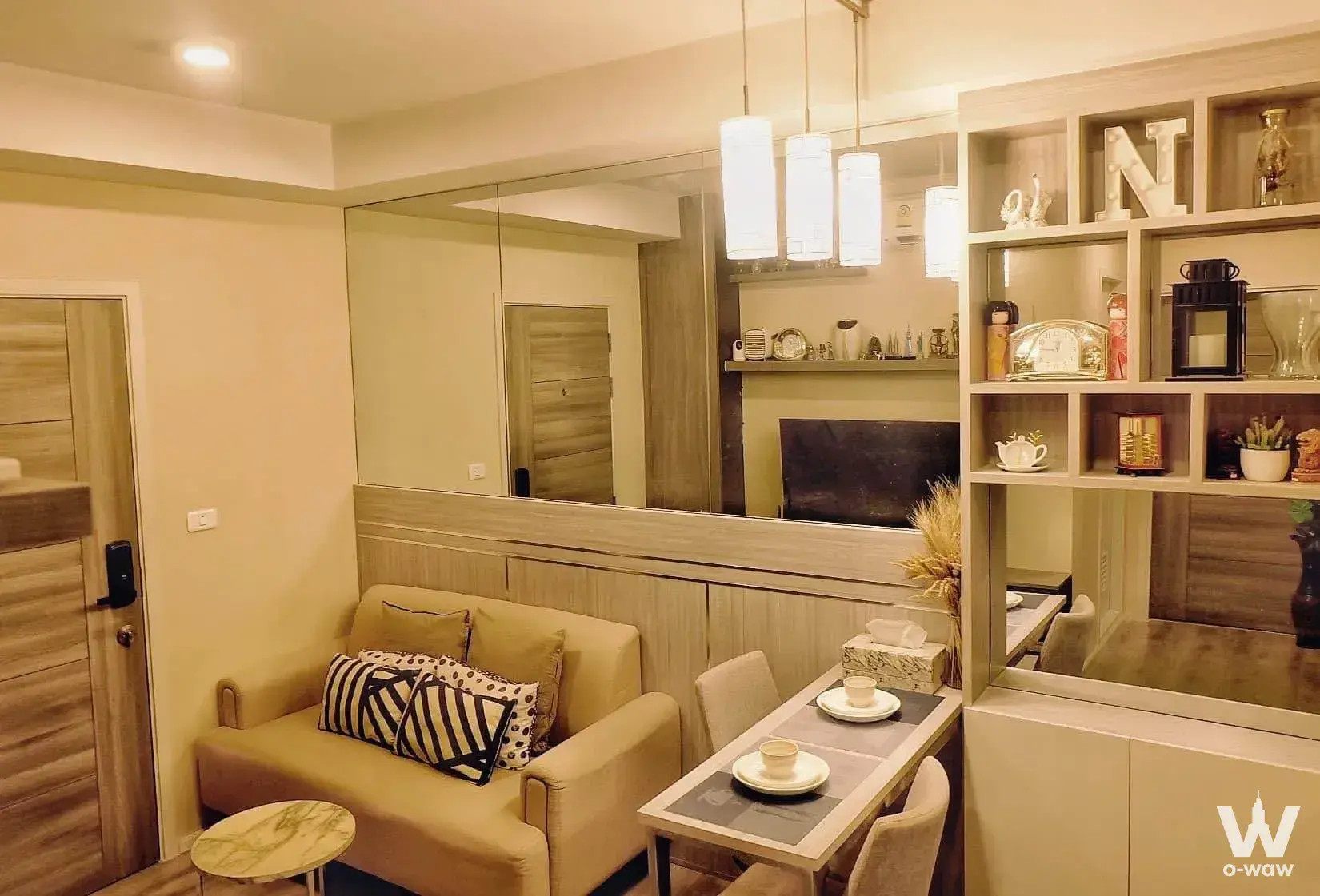 Tan sofa, marble side table, and mirrored shelving unit in modern studio apartment interior
