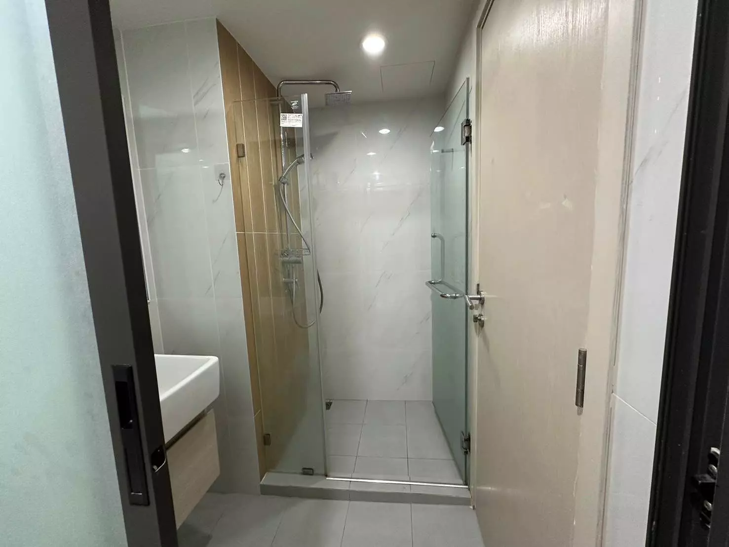Modern bathroom in The Excel Hideaway Sukhumvit 50 1-bed rental featuring glass shower and wood vanity