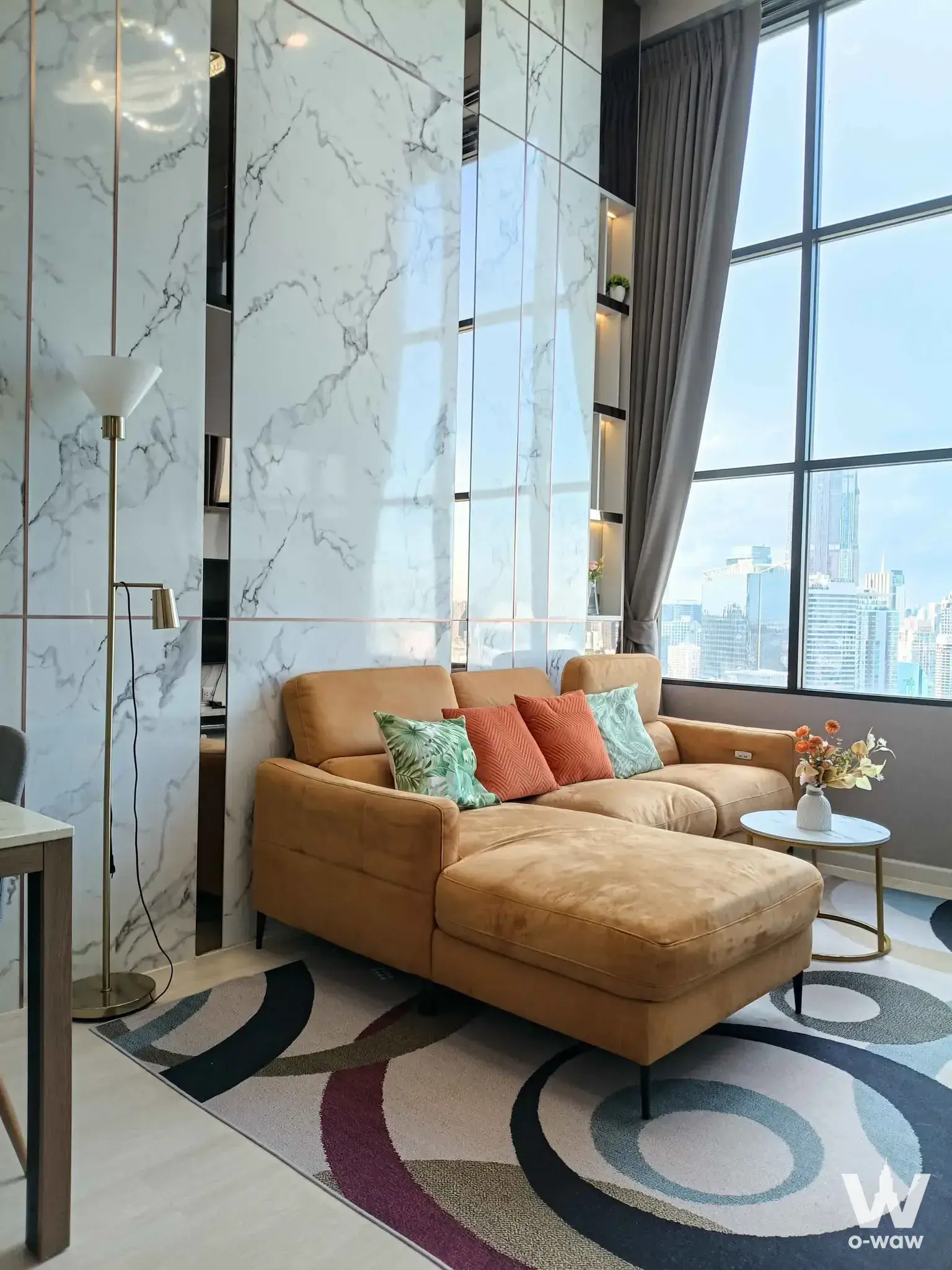 KnightsBridge Prime Sathon living room with yellow sectional sofa, marble accent wall, and city view