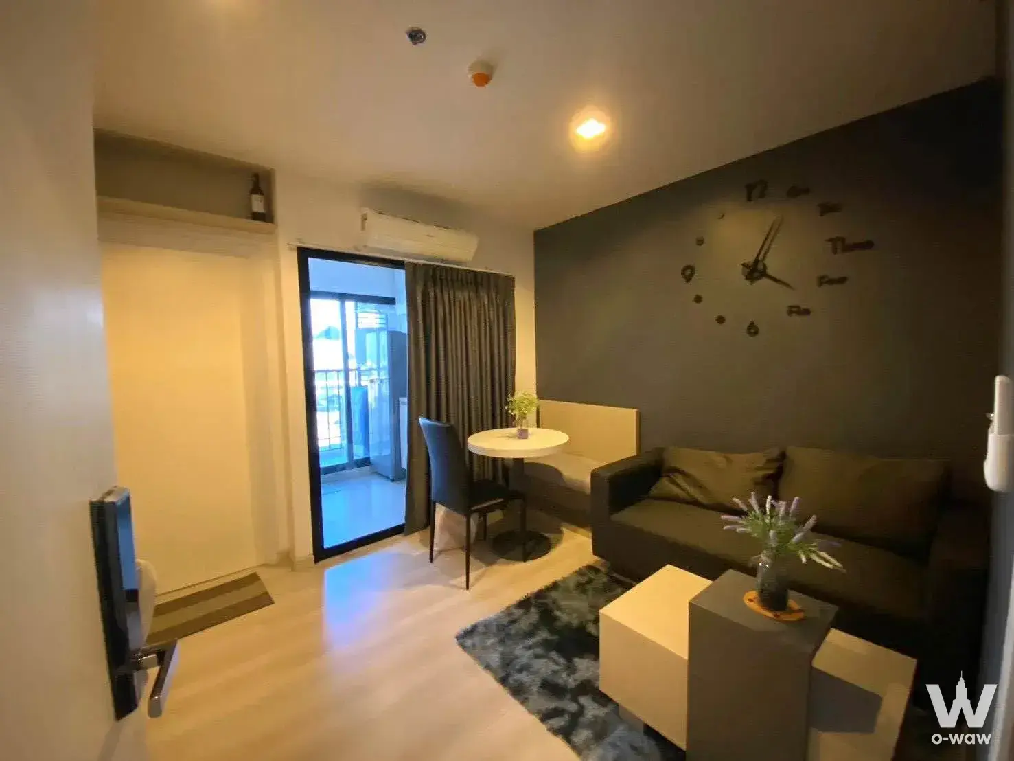 Compact living area with grey sofa and dining nook in Skyline Rattanathibet studio