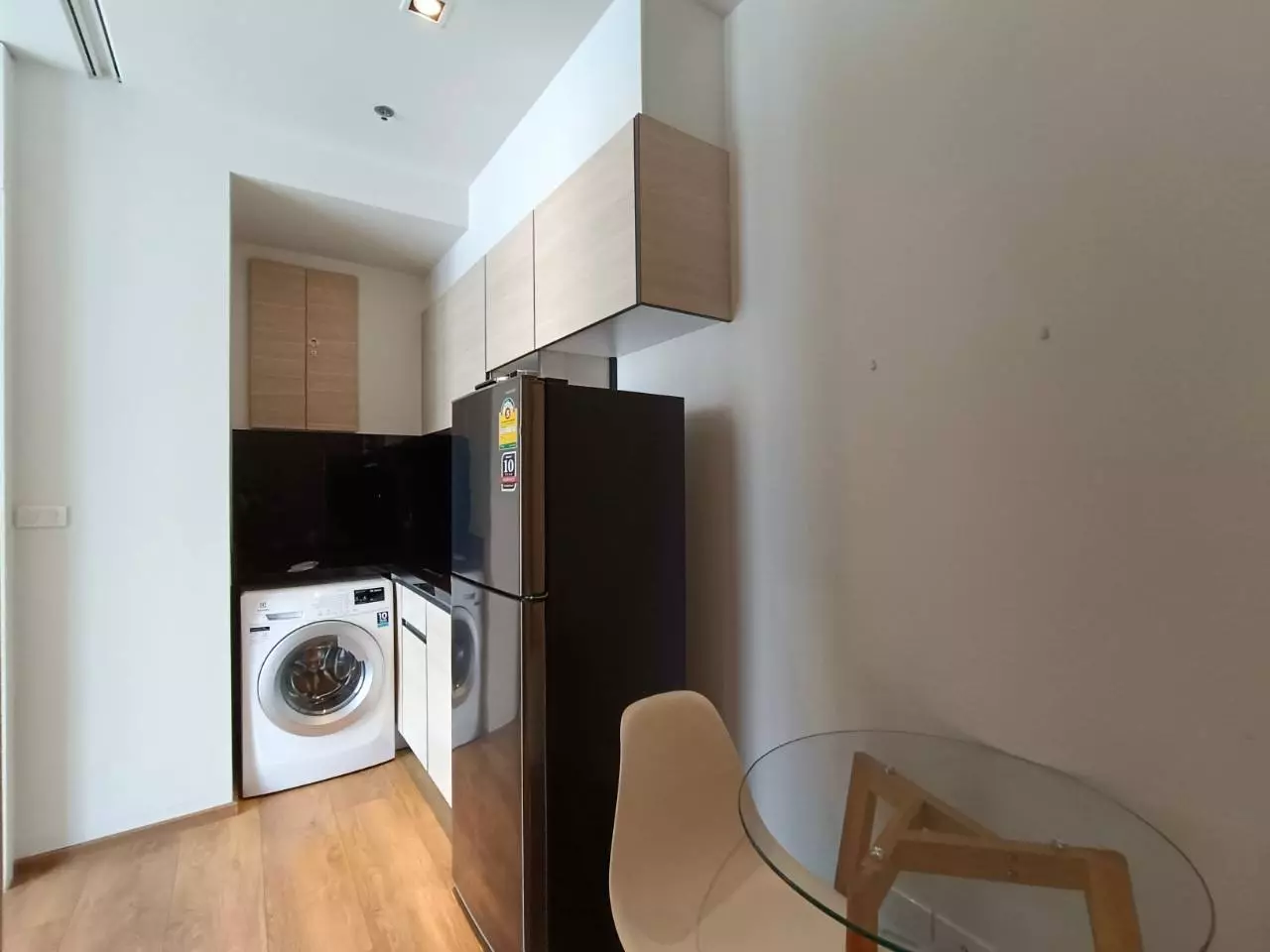 Compact kitchen with black cabinets and dining table in 1-bed unit for rent at Park24