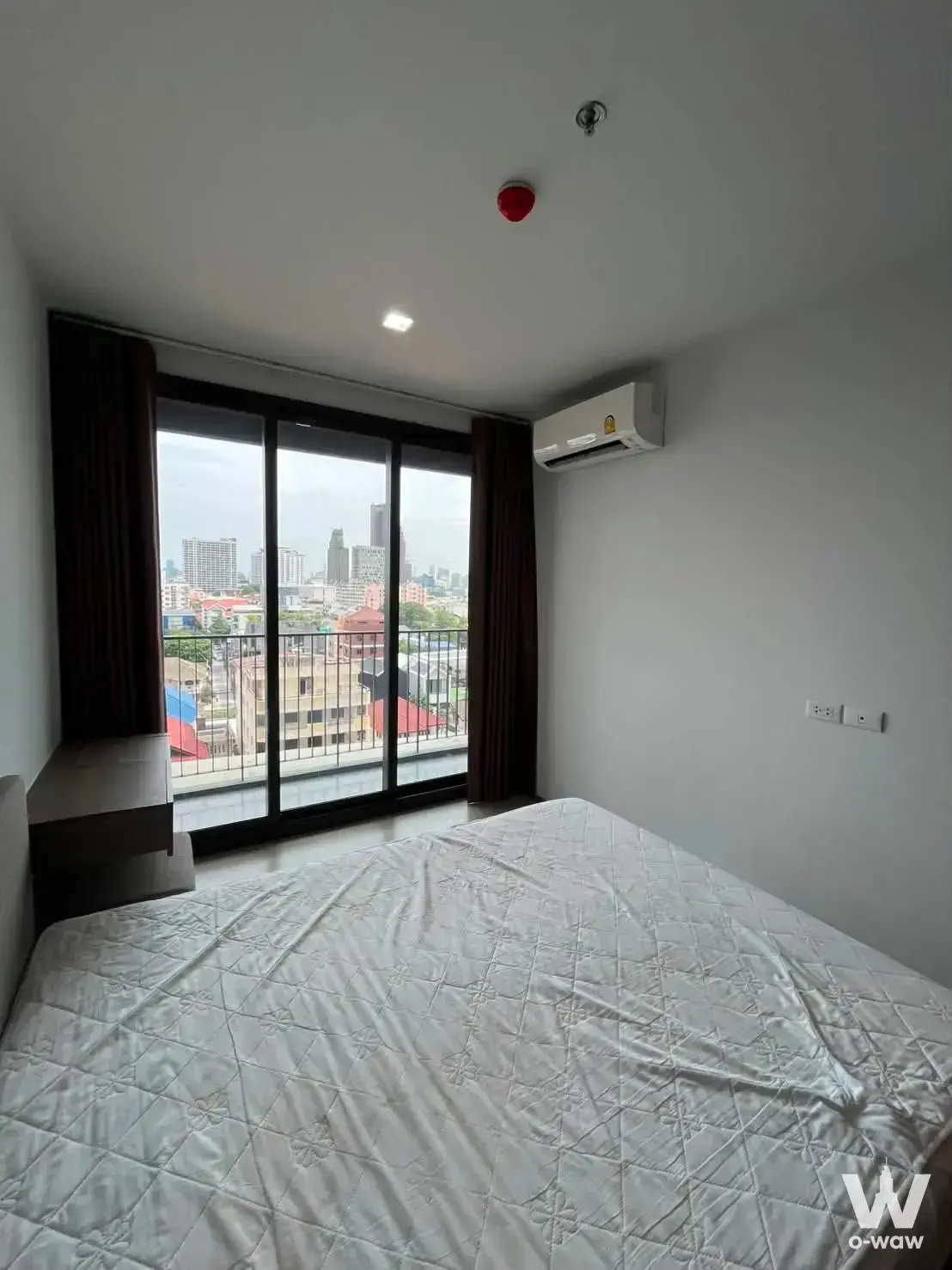 Minimalist bedroom in a 1-bed condo for rent at THE LINE Phahonyothin Park with sliding doors to a city-view balcony