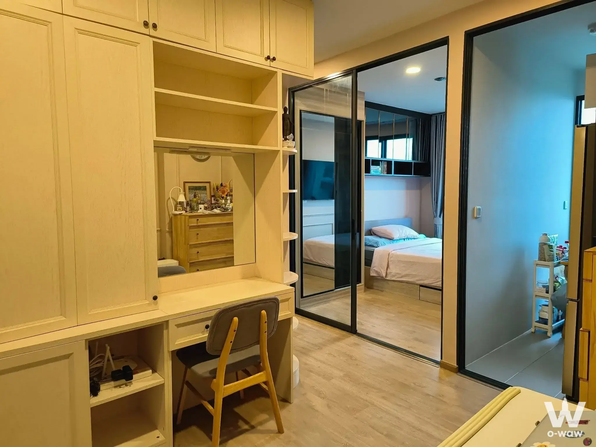 Modern bedroom in Chewathai Kaset-Nawamin condo featuring built-in white wardrobe vanity and glass sliding doors