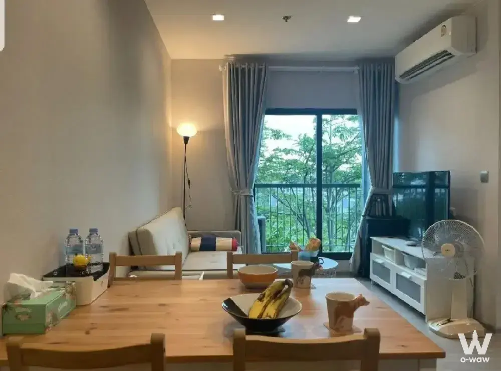 Dining area with wooden table and living space in Life Sukhumvit 62 condo