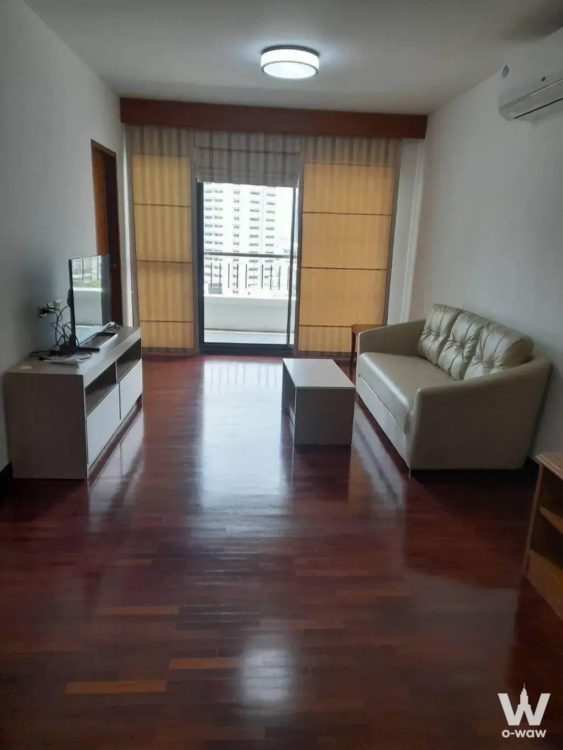 Grand Diamond Suites Hotel commercial unit with dark wood floors, beige leather sofa, and city view