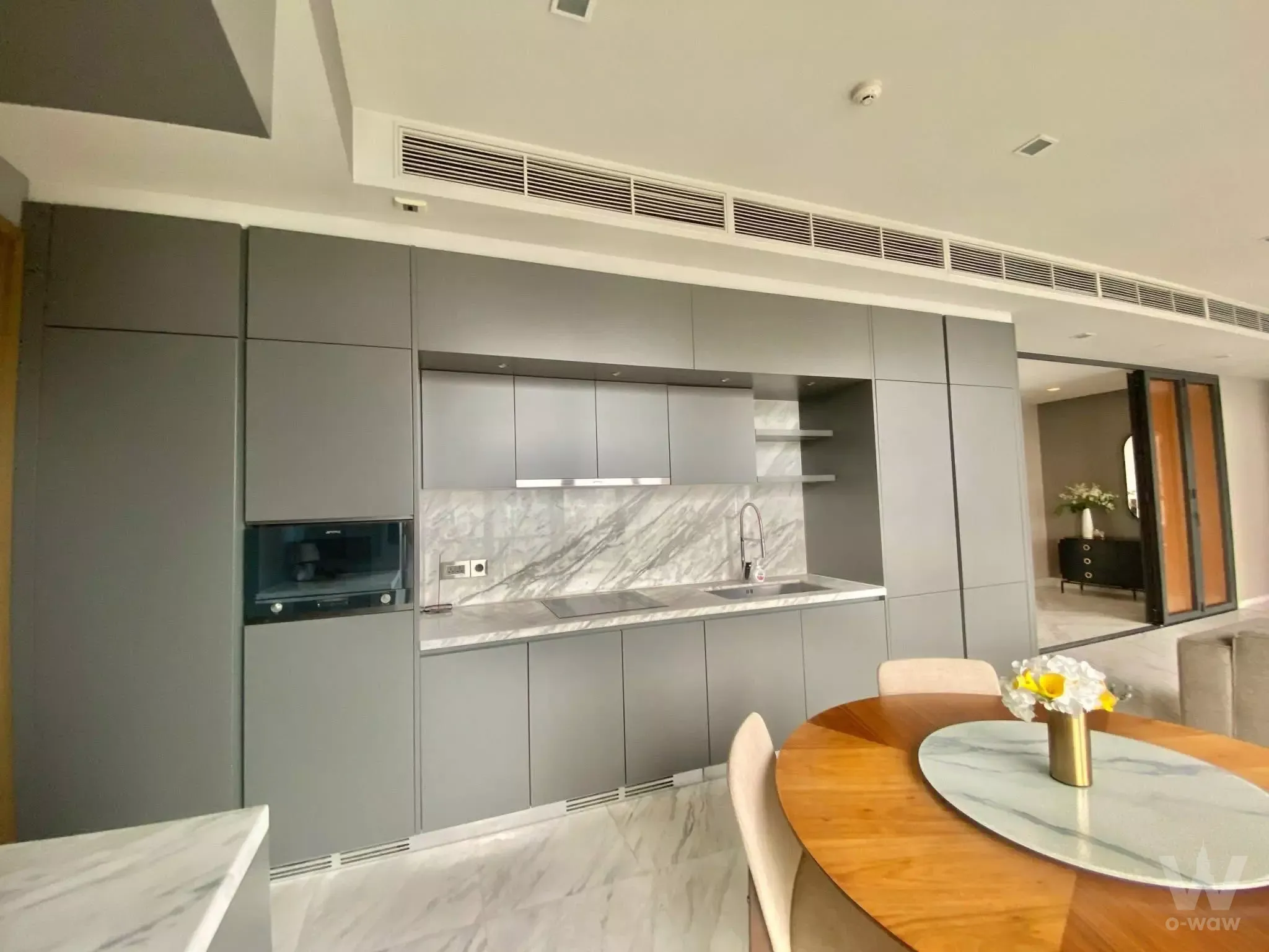 The Monument Thong Lo 2-bed condo kitchen with grey cabinets, marble counters, and round dining table