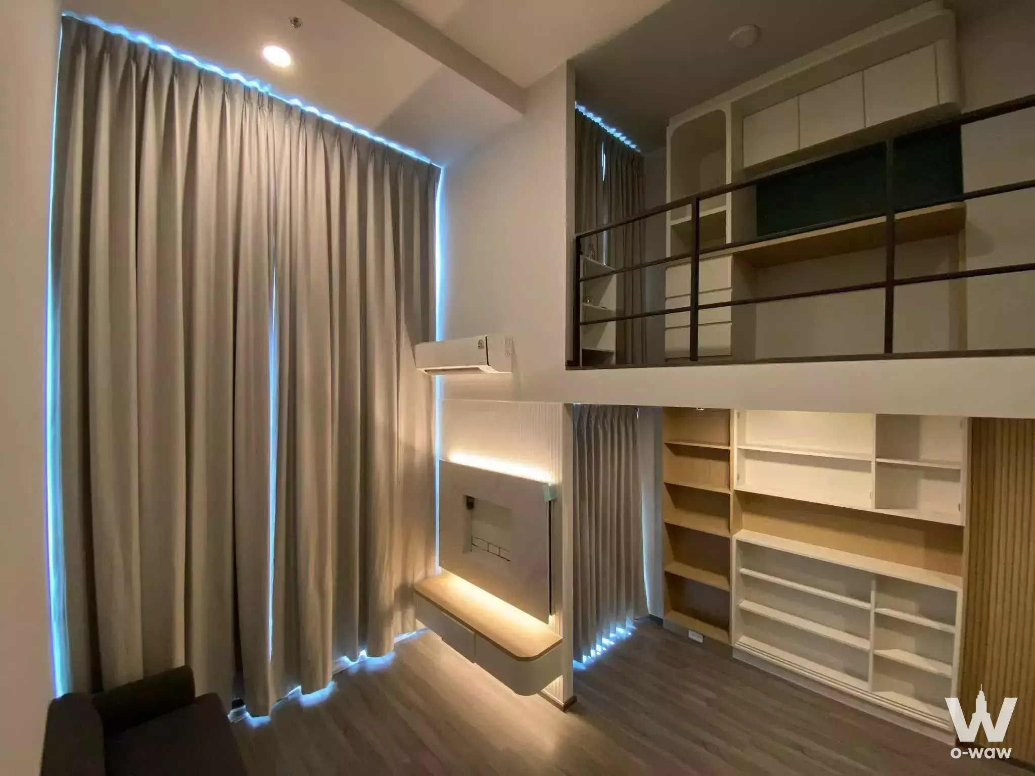 Loft bedroom with mezzanine sleeping area, built-in white cabinetry, and blue LED accent lighting